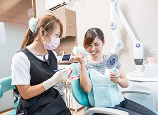 歯科助手が患者に楽しそうに指導している写真